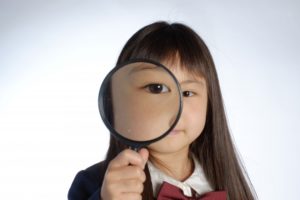 女の子が虫眼鏡で目を拡大させている写真