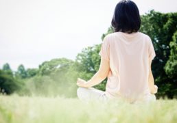 瞑想をしてリラックスする女性の後ろ姿の写真