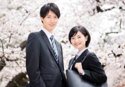 桜の前に佇む新入社員男女の写真